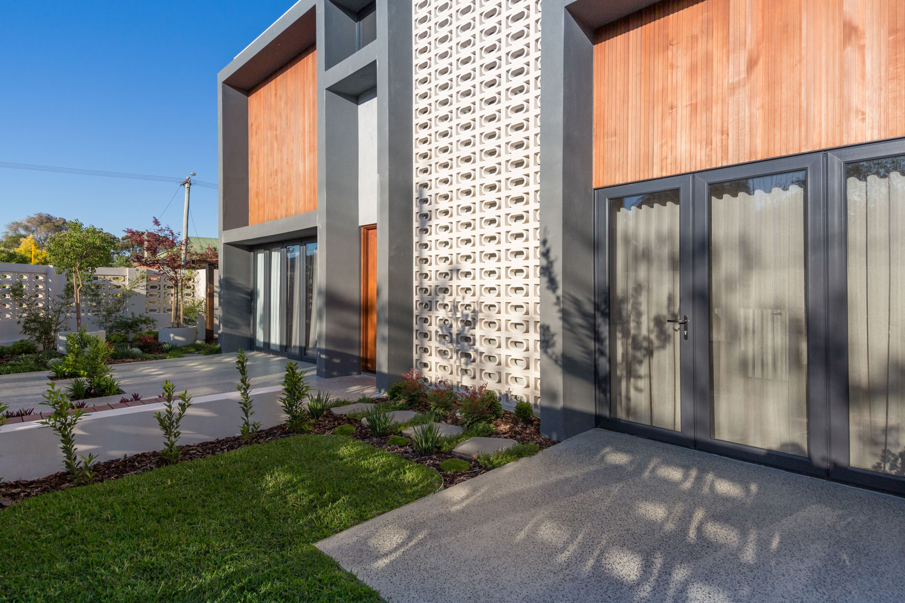 Contemporary luxury home exterior with timber cladding, modern architectural lines and landscaped front garden